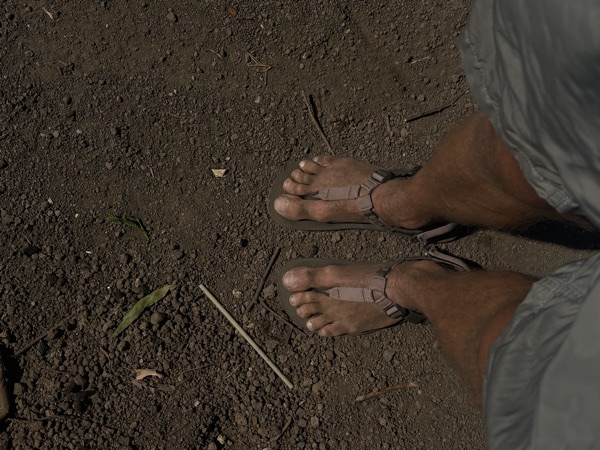 Feet in sandals on volcanic sand